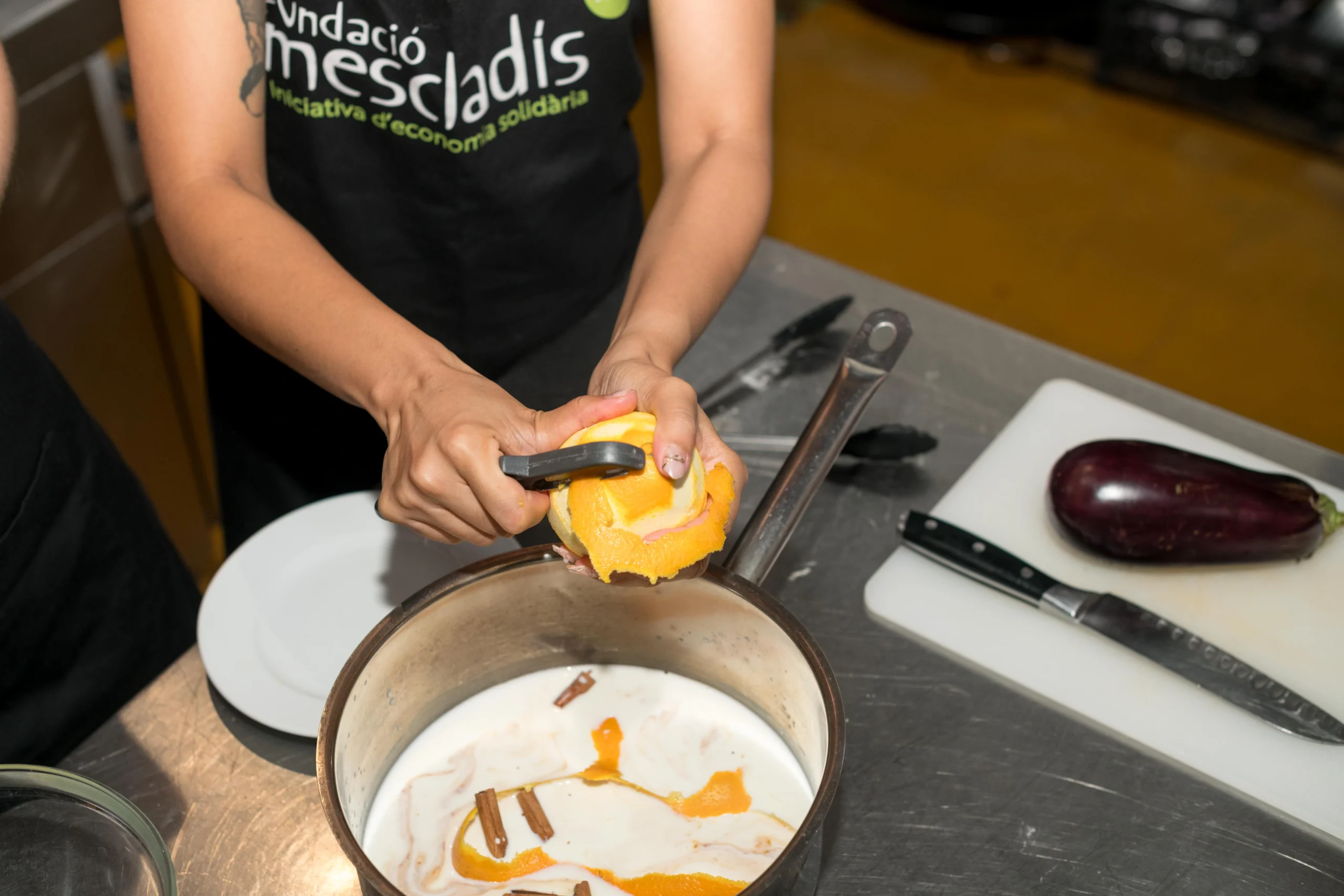 Guest putting orange rind into cooking pan during Barcelona Cooking Class for Social Good