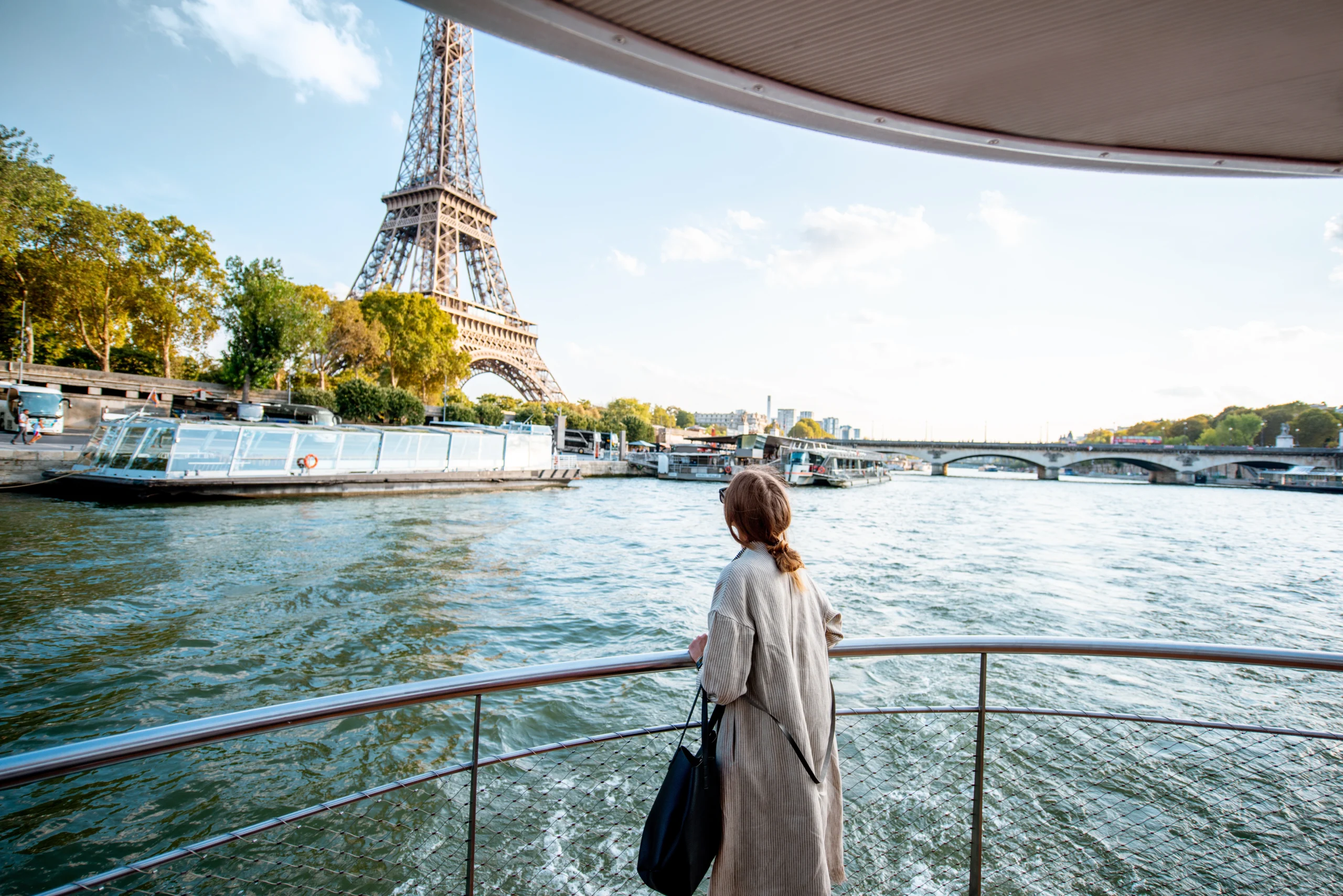 Young woman enjoying beautiful landscape view on the riverside with Eiffel tower from the private boat in Paris