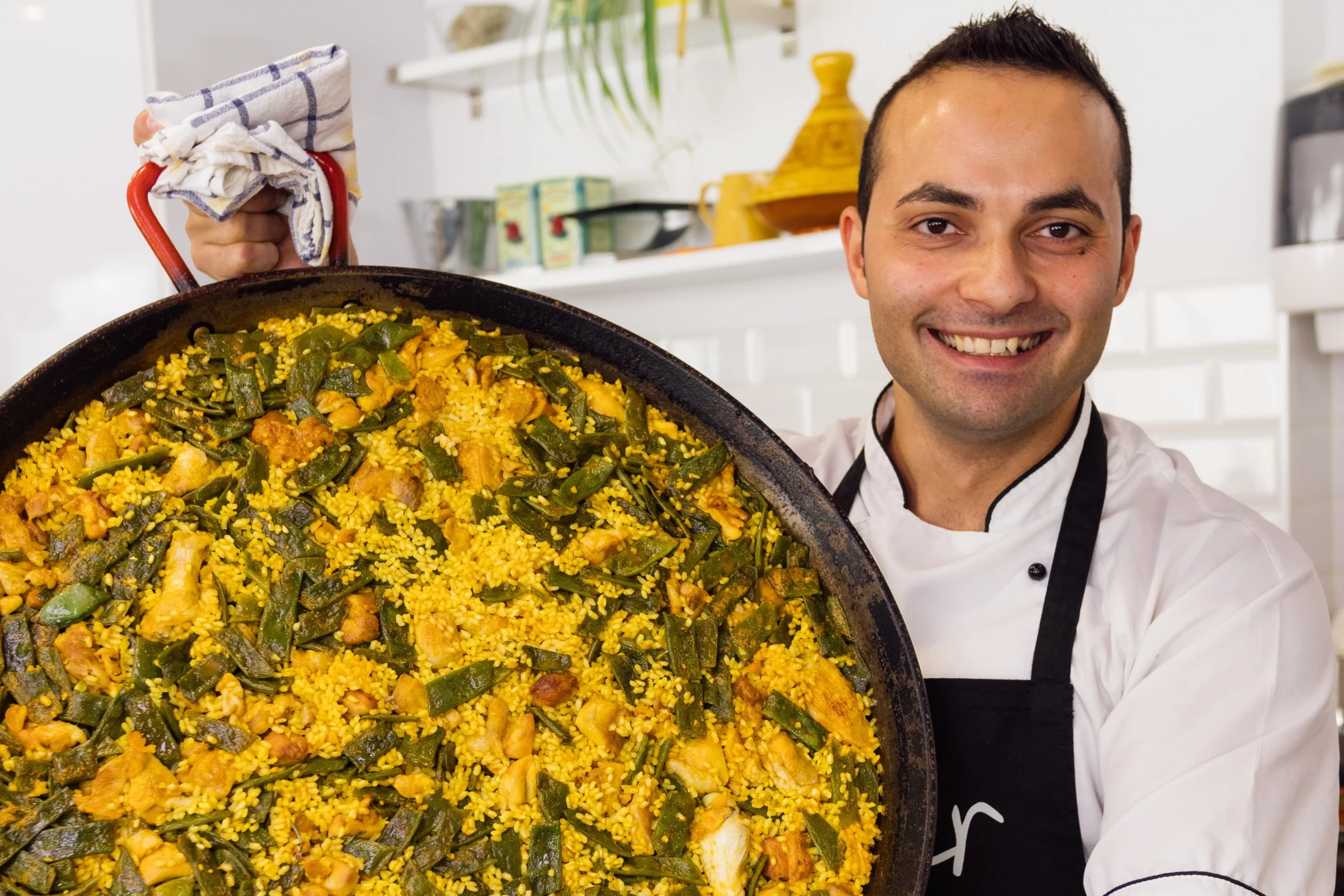 Chef posing with big paella during Spanish Cooking Class and Triana Market experience