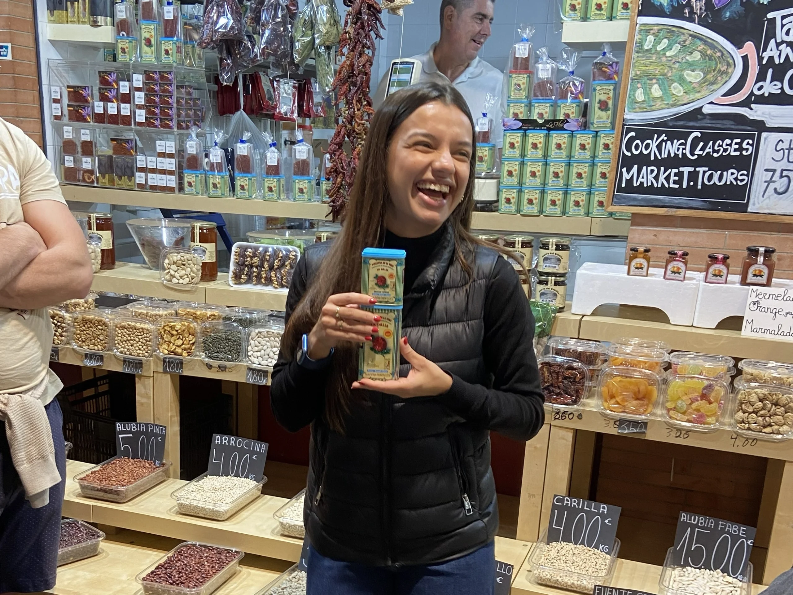 Guide holding market goods and explaining to guests during Spanish Cooking Class and Triana Market experience in Seville