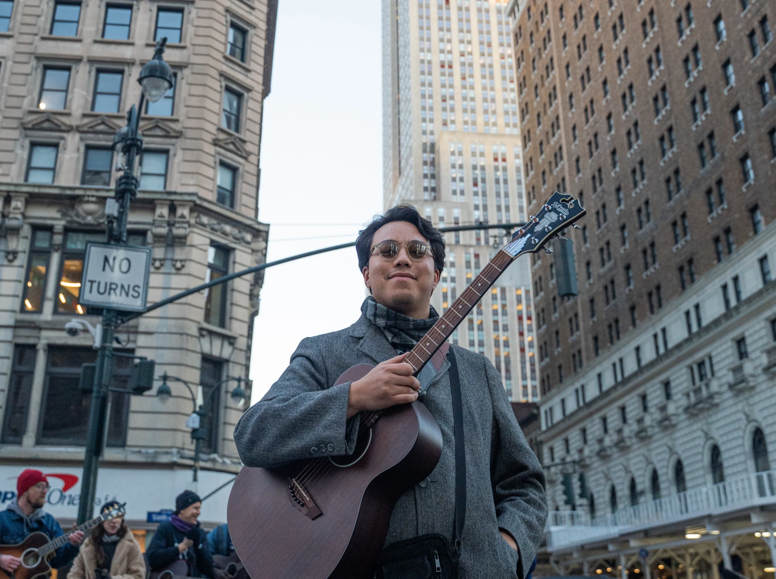 Man posing with guitar near Empire State Building in NYC