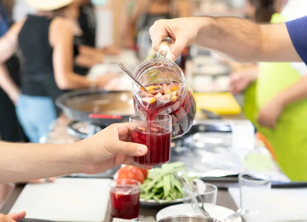 Pouring red wine sangria into a glass during cooking class in Seville