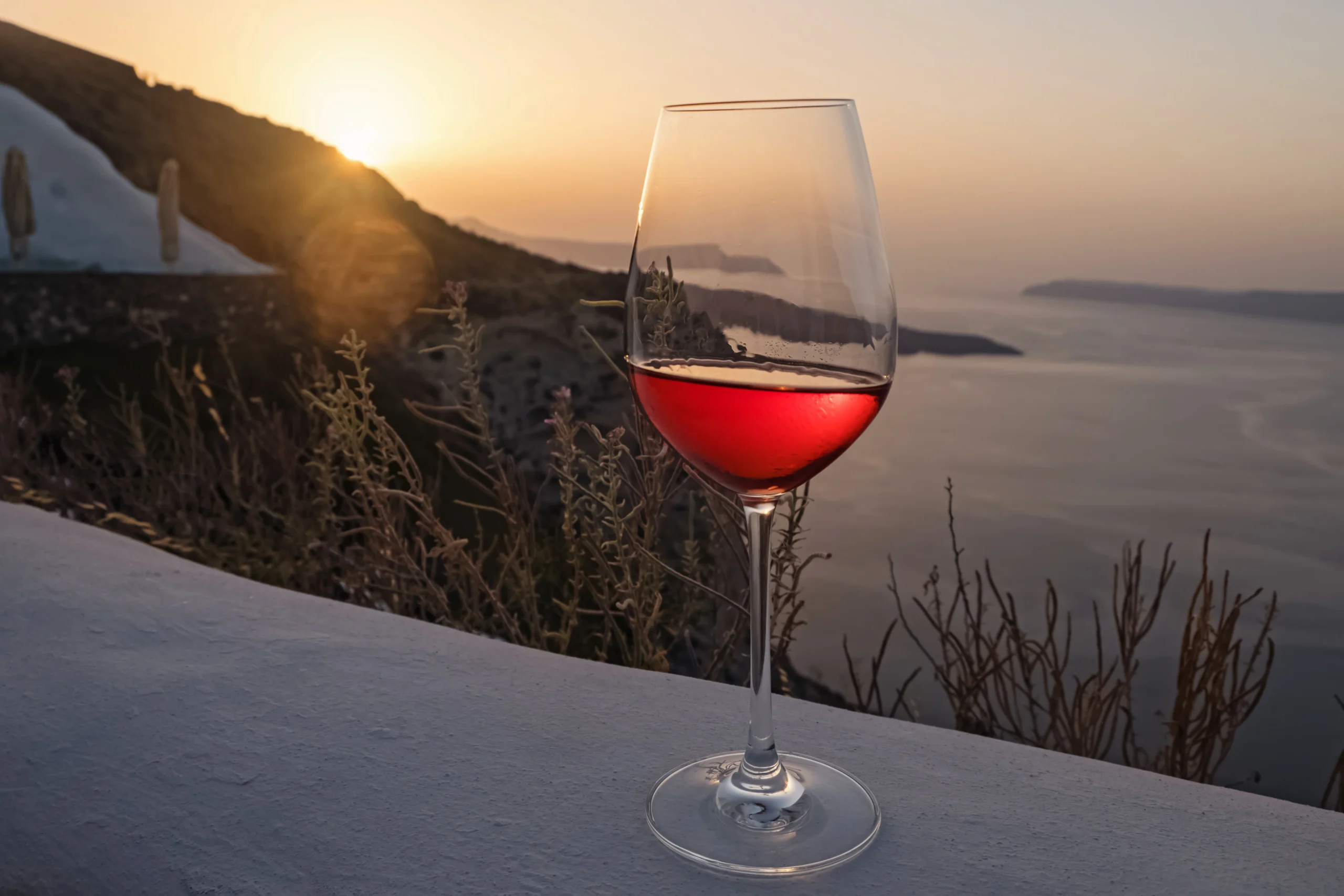 Glass of a rose wine during sunset in Santorini Greece