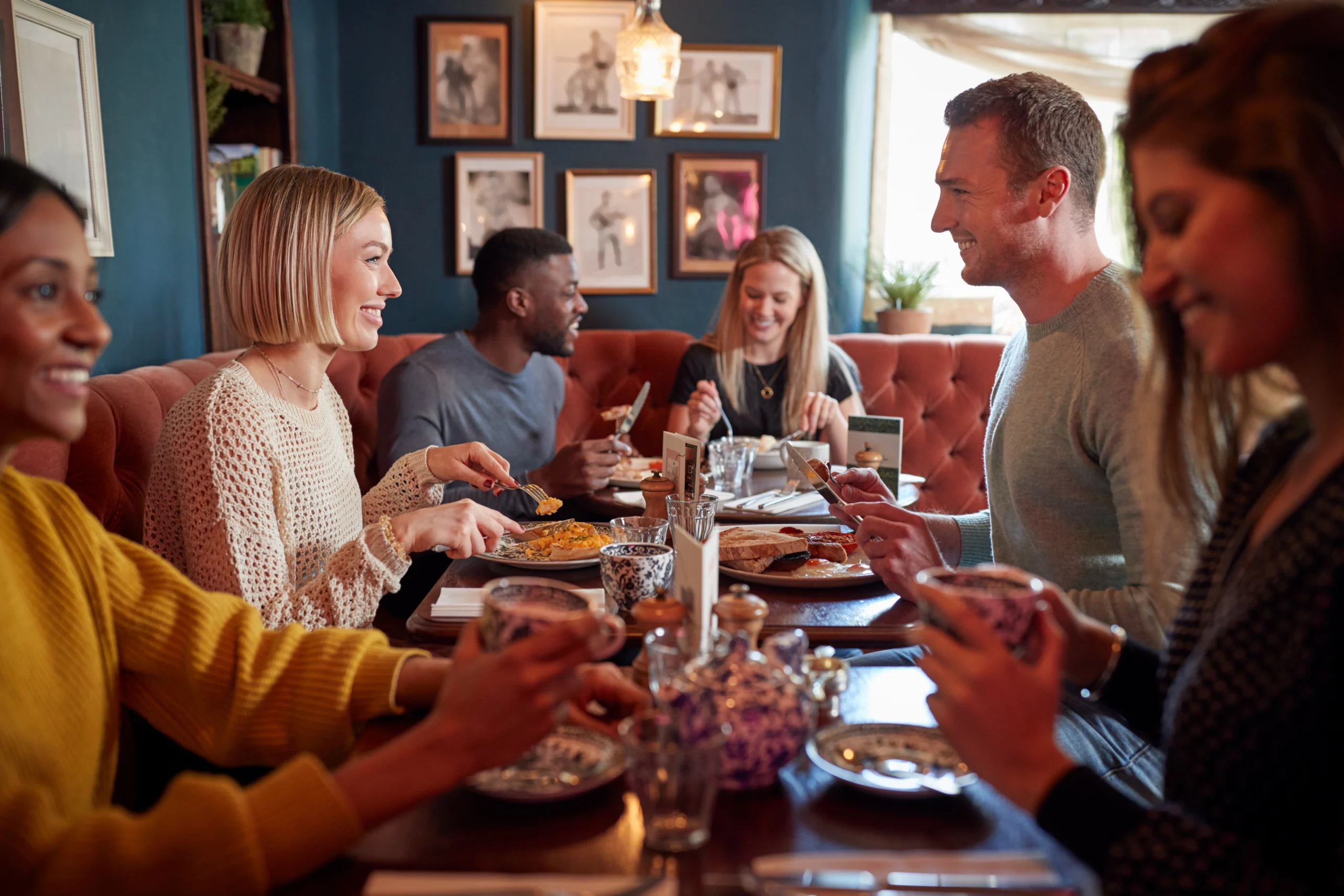 Group Of People Eating In Restaurant Of Busy Traditional English Pub