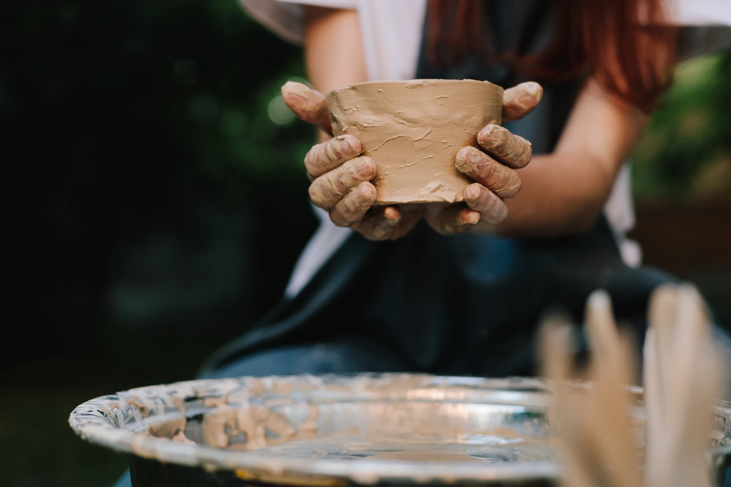 Handmade clay bowl is held after removal from the wheel