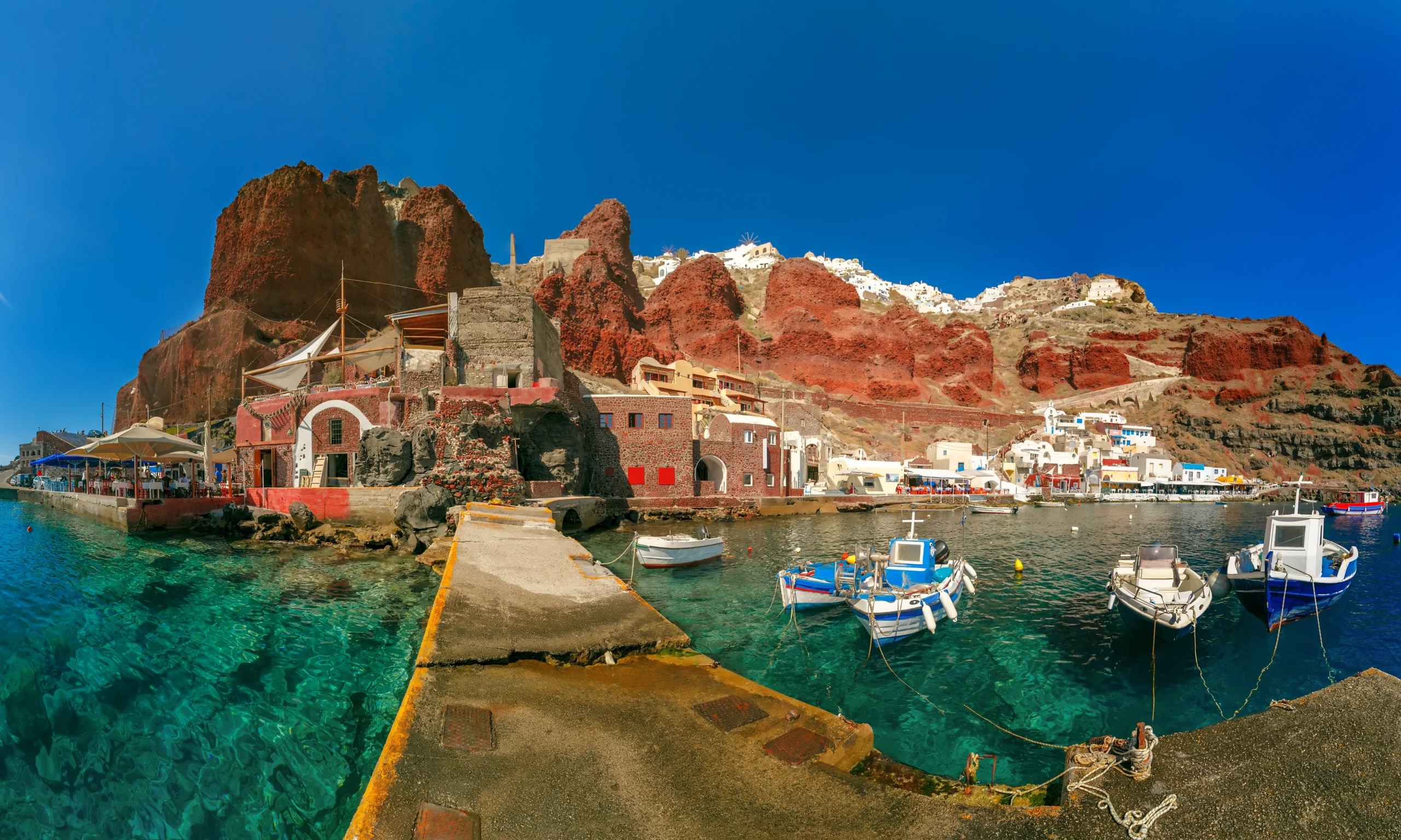 Panoramic view with fishing boats at Old port Amoudi of Oia village at Santorini island