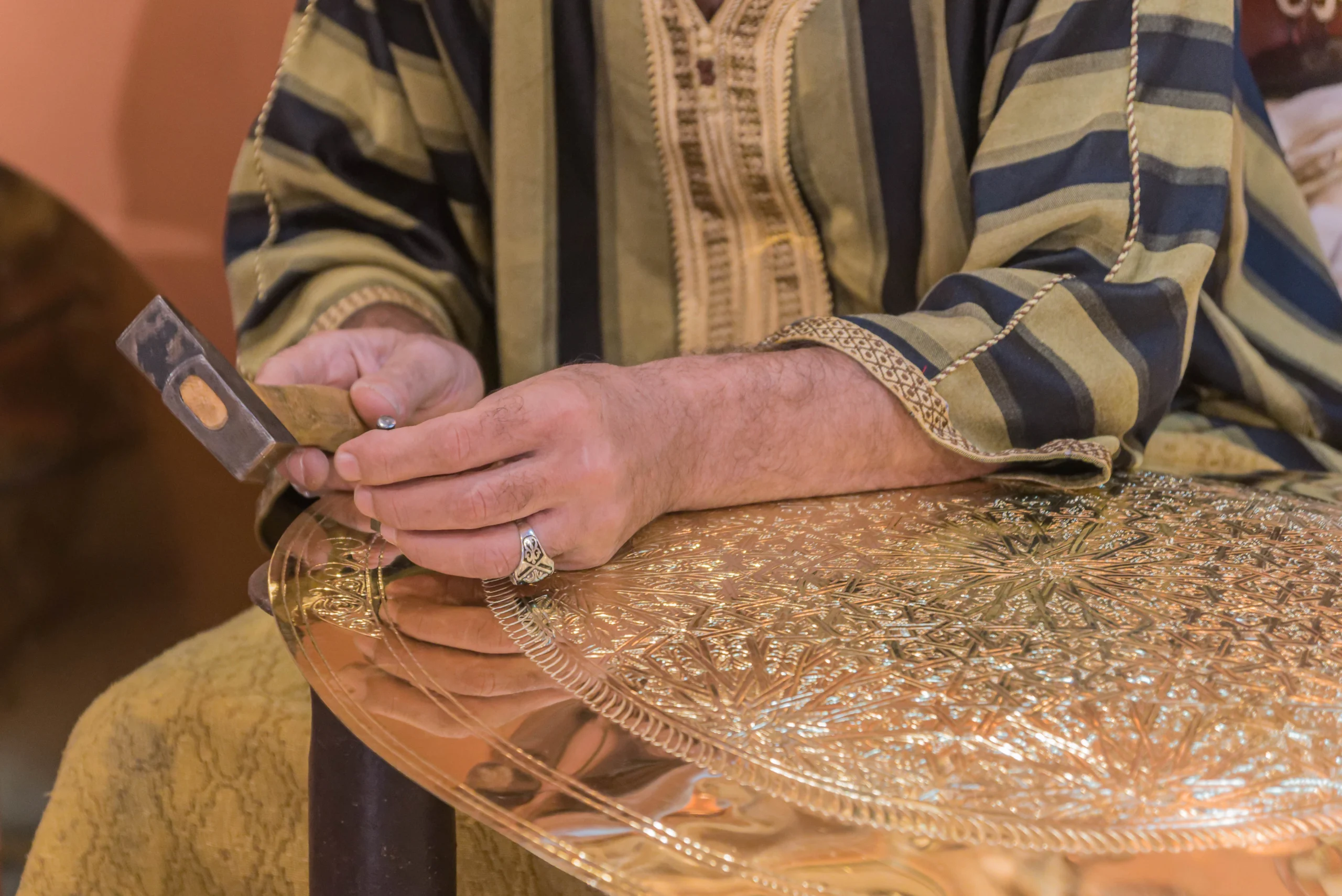 Person creating artwork on metal in Marrakech during Artisan Workshops With a Local Designer tour