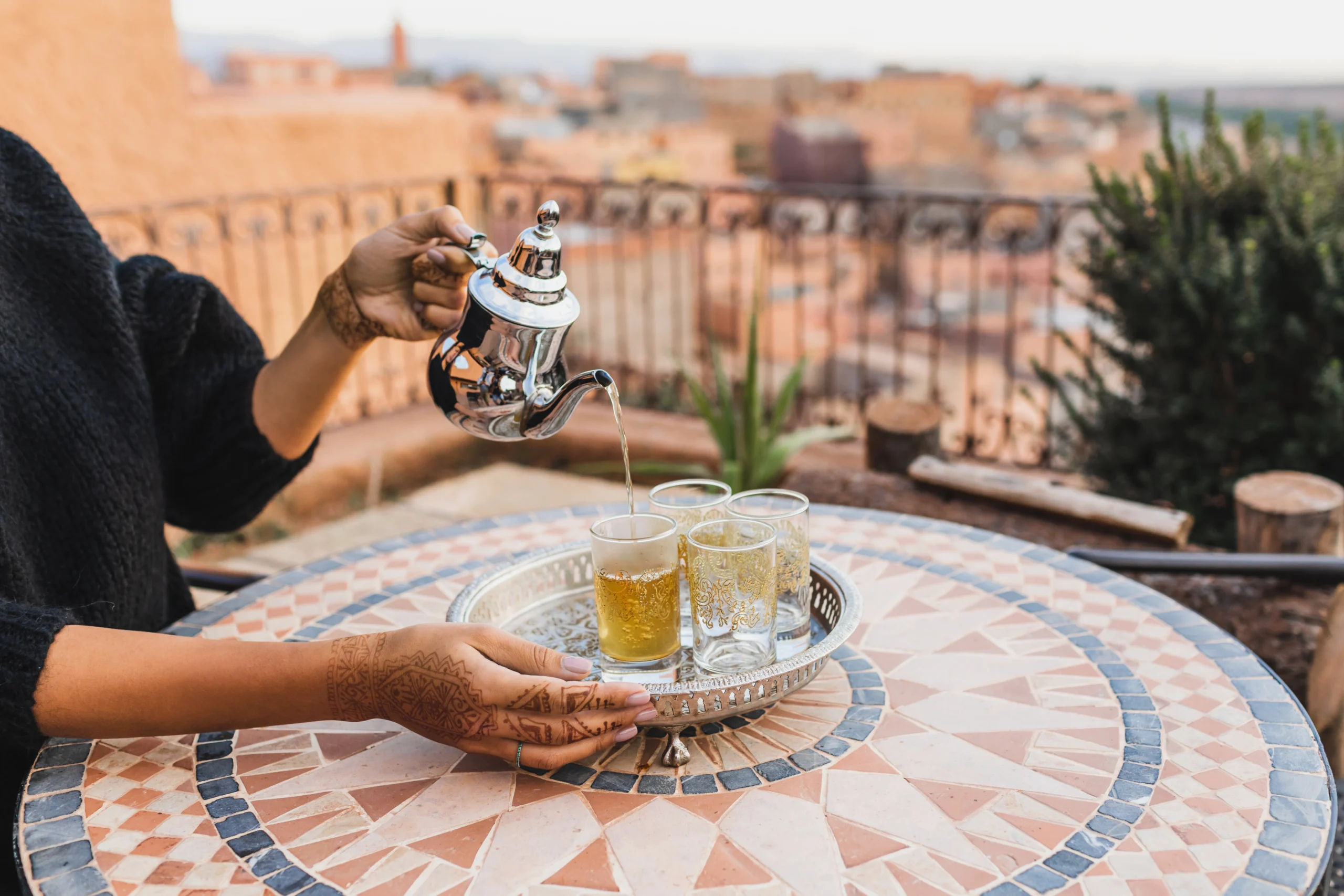 Woman hand pouring traditional moroccan mint tea in glasses during Moroccan Family Kitchen experience in Marrakech