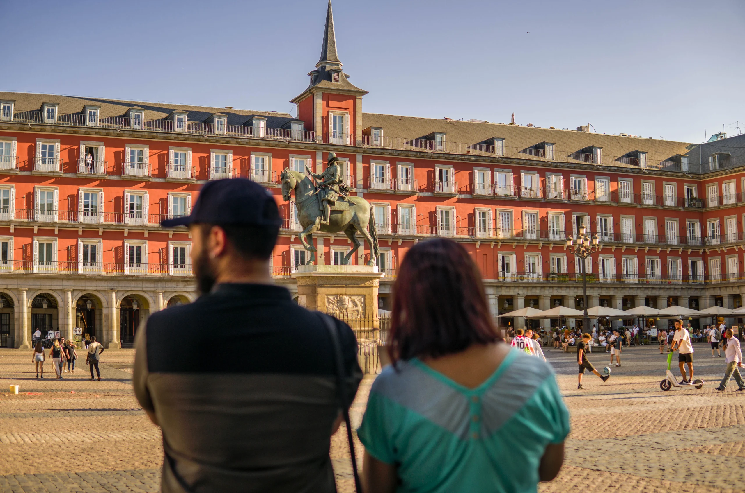 Couple visiting Madrid's Plaza Mayor with its Red Building and Statue in the Center during Madrid by E-Bike experience