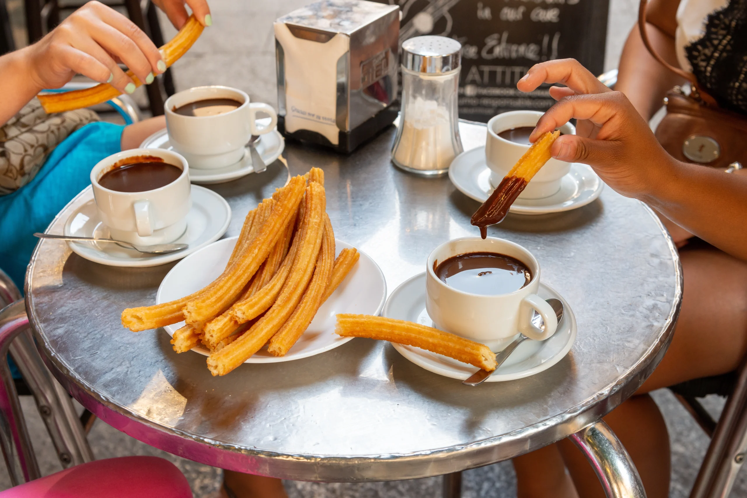People eating churros and hot chocolate drinks during Madrid by E-Bike experience